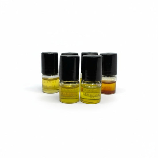 A group of small Lazaval Discovery Set perfume oil vials with black caps, filled with golden and amber natural perfume oils, arranged on a white background.